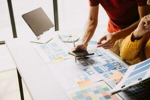 Close up ux developer and ui designer brainstorming about mobile app interface wireframe design on table with customer breif and color code at modern office.Creative digital development agency photo