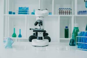 medical or scientific researcher researching and experimenting Multi-colored solution, vial and microscope In the laboratory or in the laboratory by wearing blue gloves and white clothing completely. photo