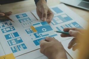 Close up ux developer and ui designer brainstorming about mobile app interface wireframe design on table with customer breif and color code at modern office.Creative digital development agency photo