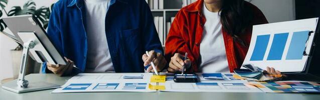 Close up ux developer and ui designer brainstorming about mobile app interface wireframe design on table with customer breif and color code at modern office.Creative digital development agency photo