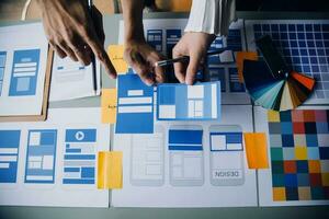 Close up ux developer and ui designer brainstorming about mobile app interface wireframe design on table with customer breif and color code at modern office.Creative digital development agency photo