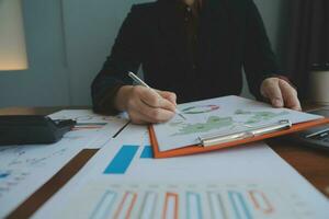 Group of confident business people point to graphs and charts to analyze market data, balance sheet, account, net profit to plan new sales strategies to increase production capacity. photo
