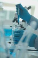 biochemical research scientist team working with microscope for coronavirus vaccine development in pharmaceutical research labolatory, selective focus photo