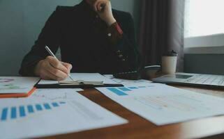 Group of confident business people point to graphs and charts to analyze market data, balance sheet, account, net profit to plan new sales strategies to increase production capacity. photo
