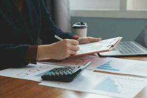 Group of confident business people point to graphs and charts to analyze market data, balance sheet, account, net profit to plan new sales strategies to increase production capacity. photo