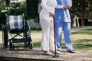 young asian physical therapist working with senior woman on walking with a walker photo