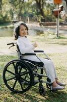 young asian physical therapist working with senior woman on walking with a walker photo