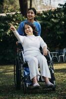 young asian physical therapist working with senior woman on walking with a walker photo