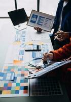 Close up ux developer and ui designer brainstorming about mobile app interface wireframe design on table with customer breif and color code at modern office.Creative digital development agency photo