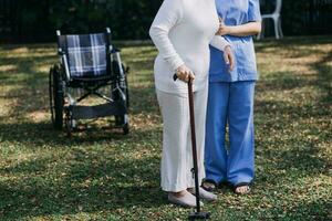 young asian physical therapist working with senior woman on walking with a walker photo