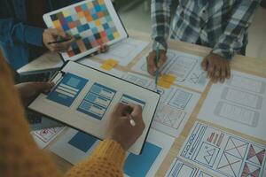 Close up ux developer and ui designer brainstorming about mobile app interface wireframe design on table with customer breif and color code at modern office.Creative digital development agency photo