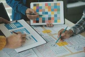 Close up ux developer and ui designer brainstorming about mobile app interface wireframe design on table with customer breif and color code at modern office.Creative digital development agency photo