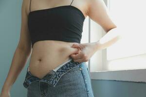 Close up of a belly with scar from c-section and abdominal fat. Women's health. A woman dressed up in sportswear demonstrating her imperfect body after a childbirth with nursery on the background. photo