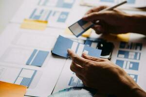 Close up ux developer and ui designer brainstorming about mobile app interface wireframe design on table with customer breif and color code at modern office.Creative digital development agency photo