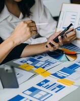 Close up ux developer and ui designer brainstorming about mobile app interface wireframe design on table with customer breif and color code at modern office.Creative digital development agency photo