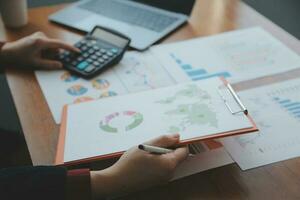 Group of confident business people point to graphs and charts to analyze market data, balance sheet, account, net profit to plan new sales strategies to increase production capacity. photo