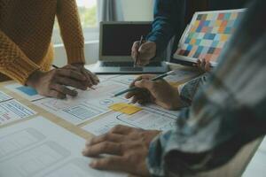 Close up ux developer and ui designer brainstorming about mobile app interface wireframe design on table with customer breif and color code at modern office.Creative digital development agency photo