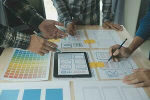 Close up ux developer and ui designer brainstorming about mobile app interface wireframe design on table with customer breif and color code at modern office.Creative digital development agency photo