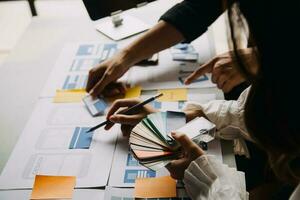 Close up ux developer and ui designer brainstorming about mobile app interface wireframe design on table with customer breif and color code at modern office.Creative digital development agency photo