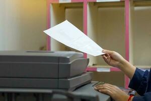 The secretary uses a copier to copy documents into a file to store in a system. soft and selective focus. photo