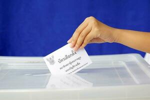 Thai people drop their ballot papers into the box to vote for members of the House of Representatives. The ballot papers are written in Thai,meaning Party-list proportional representation ballot paper photo