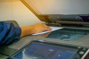 The secretary uses a copier to copy documents into a file to store in a system. soft and selective focus. photo