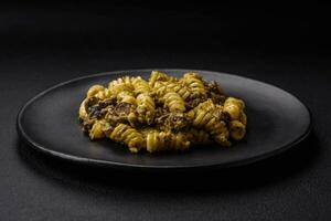 delicioso fusilli pasta con verde pesto salsa, con sal y especias foto