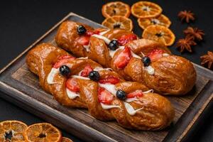 delicioso Fresco crujiente Pastelería en el formar de un coleta con fresas y arándanos foto