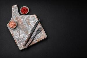 Knife, fork and cutting board, salt, pepper and other ingredients photo