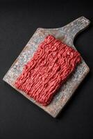 Raw ground beef or pork on a wooden cutting board with spices and salt photo