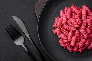 Delicious fusilli pasta with beetroot pesto, parmesan, salt and spices photo