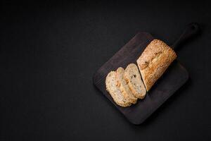 Crispy wheat flour baguette with sesame seeds on a wooden cutting board photo