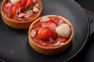 Delicious fresh sweet tartlets with strawberries and coconut flakes photo