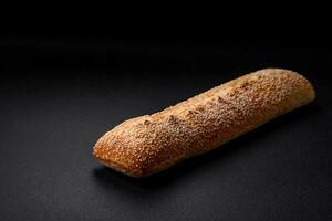 Crispy wheat flour baguette with sesame seeds on a wooden cutting board photo