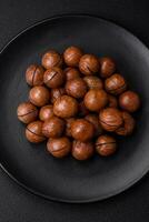 Delicious roasted macadamia nuts in shell on a dark textured background photo