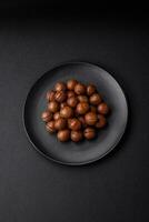 Delicious roasted macadamia nuts in shell on a dark textured background photo