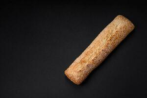 Crispy wheat flour baguette with sesame seeds on a wooden cutting board photo