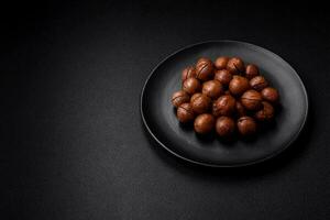 Delicious roasted macadamia nuts in shell on a dark textured background photo