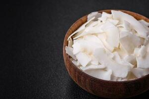 White dry coconut flakes in a wooden bowl prepared for making desserts photo