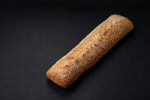 Crispy wheat flour baguette with sesame seeds on a wooden cutting board photo