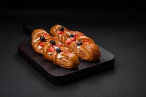 Delicious fresh crispy pastry in the form of a pigtail with strawberries and blueberries photo