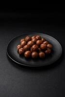 Delicious roasted macadamia nuts in shell on a dark textured background photo