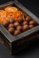 Delicious roasted macadamia nuts in shell on a dark textured background photo