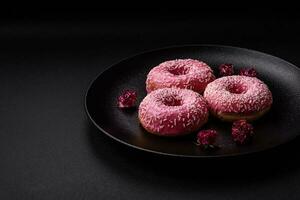 Delicious fresh sweet donuts in pink glaze with strawberry filling photo