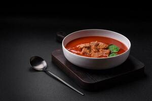 Delicious fresh gazpacho with breadcrumbs, salt and spices in a ceramic plate photo