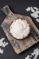 White dry coconut flakes in a wooden bowl prepared for making desserts photo