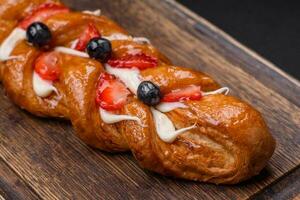 Delicious fresh crispy pastry in the form of a pigtail with strawberries and blueberries photo