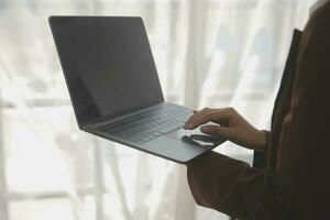 atractivo sonriente joven asiático negocio mujer trabajo a hogar oficina, asiático mujer trabajando en ordenador portátil computadora participación tableta. foto