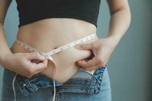 fat woman, fat belly, chubby, obese woman hand holding excessive belly fat with measure tape, woman diet lifestyle concept photo