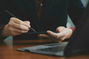 Asian Businesswoman Using laptop computer and working at office with calculator document on desk, doing planning analyzing the financial report, business plan investment, finance analysis concept. photo